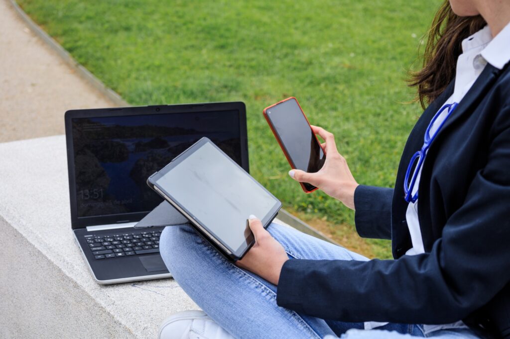 Entrepreneur working with multiple devices sitting in a bench in a trendy park. Close-up view.